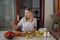 Young caucasian woman cooking fresh fruit and vegetable salad on table. Person preparing healthy yummy eating lunch in