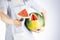 A young caucasian woman is cutting a wedge out of a ripe watermelon using a knife