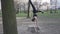 A young Caucasian woman does a handstand in a wooded area, leaning her hands on a stump tree. Healthy Lifestyle female