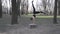 A young Caucasian woman does a handstand in a wooded area, leaning her hands on a stump tree. Healthy Lifestyle female