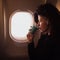 Young Caucasian woman drinking coffee inside airplane sitting