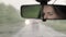 Young Caucasian Woman Driving Car in Rear View Mirror at Heavy Rain