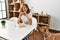 Young caucasian woman eating classical hamburger sitting on table at home