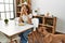 Young caucasian woman eating classical hamburger sitting on table at home