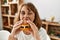 Young caucasian woman eating classical hamburger sitting on table at home