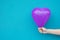 Young Caucasian Woman Girl Holds in Hand Purple Heart Shaped Air Balloon on Turquoise Painted Wall Background. Love Charity