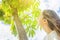 Young Caucasian Woman Girl with Long Chestnut Hair Standing under tree looking up in the sky green foliage