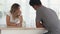 Young caucasian woman with glass of water sitting by the table talking with her african boyfriend. Happy family enjoy