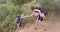 Young Caucasian woman helps her biracial friend up a steep trail