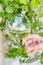 Young caucasian woman hold in hand tilted glass of white dry wine on green foliage vines background. Authentic lifestyle