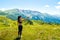 Young caucasian woman hold mini white alpine color drone in scenic nature mountains outdoors .Filmmaker shoot drone footage for