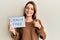 Young caucasian woman holding cruelty free message paper smiling happy and positive, thumb up doing excellent and approval sign