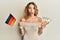 Young caucasian woman holding germany flag and euros banknotes afraid and shocked with surprise and amazed expression, fear and