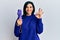 Young caucasian woman holding purple closed umbrella doing ok sign with fingers, smiling friendly gesturing excellent symbol