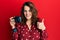 Young caucasian woman holding reflex camera smiling happy and positive, thumb up doing excellent and approval sign