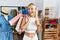 Young caucasian woman holding shopping bags at retail shop doing happy thumbs up gesture with hand