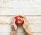 Young caucasian woman holds in hands ripe red apple on white plank wood background. Thanksgiving autumns harvest gratefulness