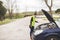 Young Caucasian woman looking at car engine, she doesn`t know what to do, car broken down in the middle of the road. Automobile