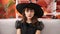 Young caucasian woman looking serious wearing witch costume sitting on the sofa at home