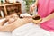 Young caucasian woman lying on table having back chocolate treatment at beauty salon