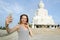 Young caucasian woman making selfie by smartphone near white statue of Buddha in Phuket.