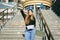 Young caucasian woman posing on street with skateboard in hands. Teenager girl in blue jeans extreme sports in an urban