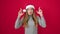 Young caucasian woman praying wearing christmas hat crossing fingers for lucky over isolated red background