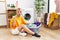 Young caucasian woman putting dirty laundry into washing machine pointing down with fingers showing advertisement, surprised face