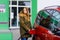 Young caucasian woman at self-service gas station, hold fuel nozzle and refuel the car with petrol, diesel, gas. Pretty