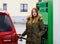 Young caucasian woman at self-service gas station, hold fuel nozzle and refuel the car with petrol, diesel, gas. Pretty