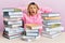 Young caucasian woman sitting on the table with books crazy and scared with hands on head, afraid and surprised of shock with open