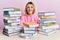 Young caucasian woman sitting on the table with books with a happy and cool smile on face