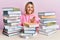 Young caucasian woman sitting on the table with books smiling cheerful offering palm hand giving assistance and acceptance