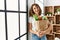 Young caucasian woman smiling confident holding groceries paper bag at home