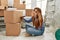 Young caucasian woman smiling confident writing books word on cardboard box at new home