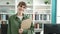 Young caucasian woman smiling wearing glasses holding clipboard at library university