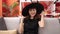 Young caucasian woman smiling wearing witch costume sitting on the sofa at home