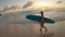 Young Caucasian woman on surfing trip in Barbados walks along beach at sunset