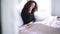 Young caucasian woman talking on the phone in bedroom. Portrait of happy curly-haired brunette girl lying in bed at home