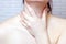 Young caucasian woman touching her neck with the hand. Sore throat, cold, neck illness and laryngitis concept.