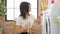 Young caucasian woman turning on washing machine reading instruction at laundry room