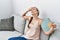 Young caucasian woman using hand fan sitting on sofa at home