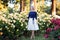 Young Caucasian woman walking in a rose garden near yellow roses. Full body portrait