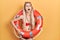 Young caucasian woman wearing bikini and holding lifeguard float angry and mad screaming frustrated and furious, shouting with