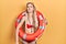 Young caucasian woman wearing bikini and holding lifeguard float looking at the camera blowing a kiss on air being lovely and sexy