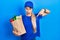 Young caucasian woman wearing courier uniform with groceries from supermarket pointing down with fingers showing advertisement,