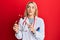 Young caucasian woman wearing doctor uniform holding tuning fork smiling looking to the side and staring away thinking