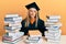 Young caucasian woman wearing graduation ceremony robe sitting on the table looking at the camera blowing a kiss on air being