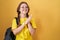 Young caucasian woman wearing student backpack over yellow background clapping and applauding happy and joyful, smiling proud