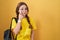 Young caucasian woman wearing student backpack over yellow background pointing to the eye watching you gesture, suspicious